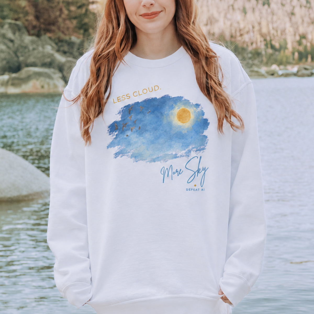 Woman wearing the Less Cloud, More Sky unisex crewneck sweatshirt by a lake